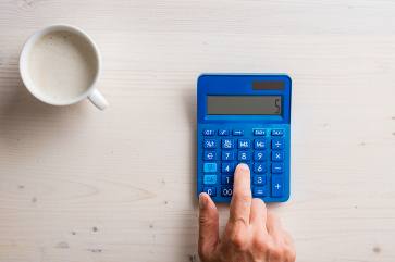 niebieski kalkulator i filiżanka kawy
